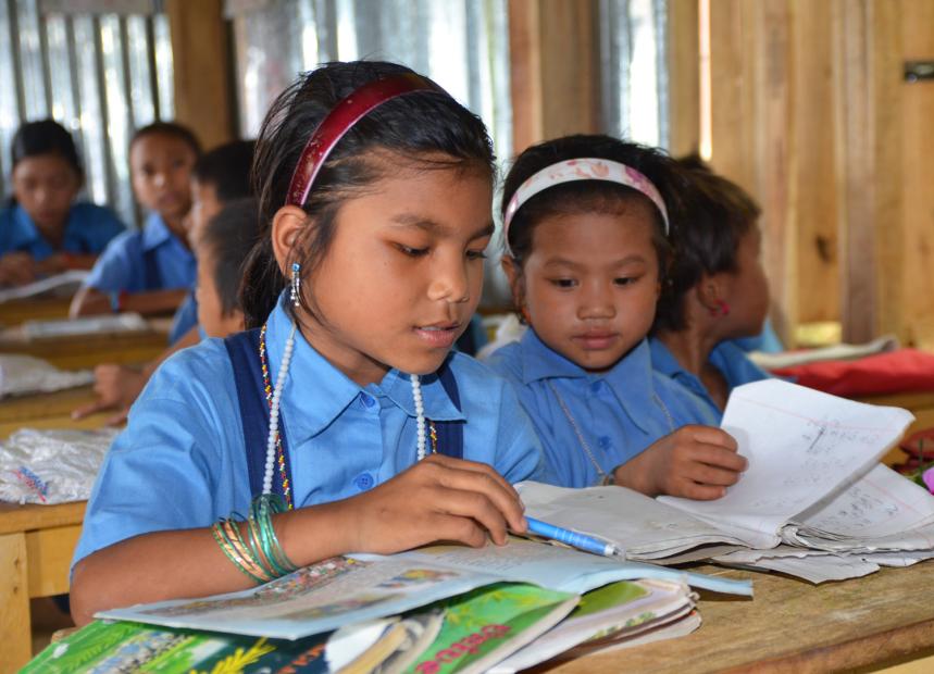 Zwei junge Mädchen lesen etwas in einer Schule in Asien, unterstützt von unserer Bildungsmission.