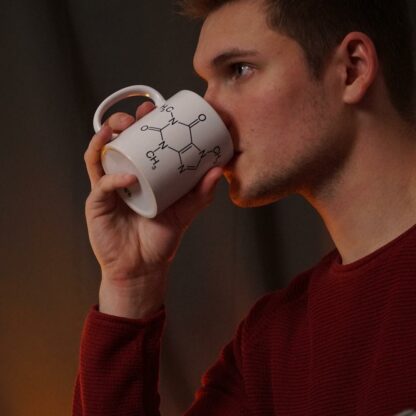 Man drinking from a mug with a caffeine molecule