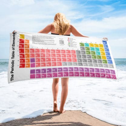 A woman holding a periodic table towel on the beach