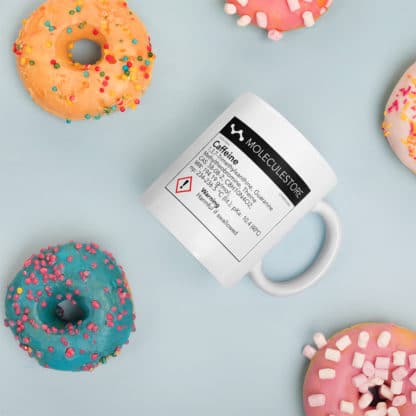 Mug with a chemical label with information about caffeine surrounded by donuts