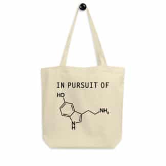 A tote bag with a print that says "In Pursuit of" followed by a serotonin molecule