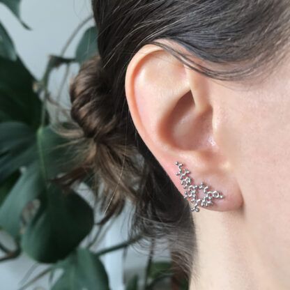 Oxytocin ear climber in silver shown in an ear