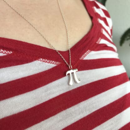 Pi necklace small silver with a chain worn by a female model